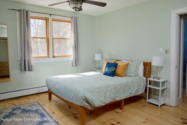 bedroom featuring a baseboard radiator, baseboards, a ceiling fan, and hardwood / wood-style flooring