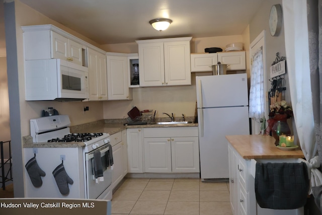 kitchen featuring white cabinets, light tile patterned floors, white appliances, and sink