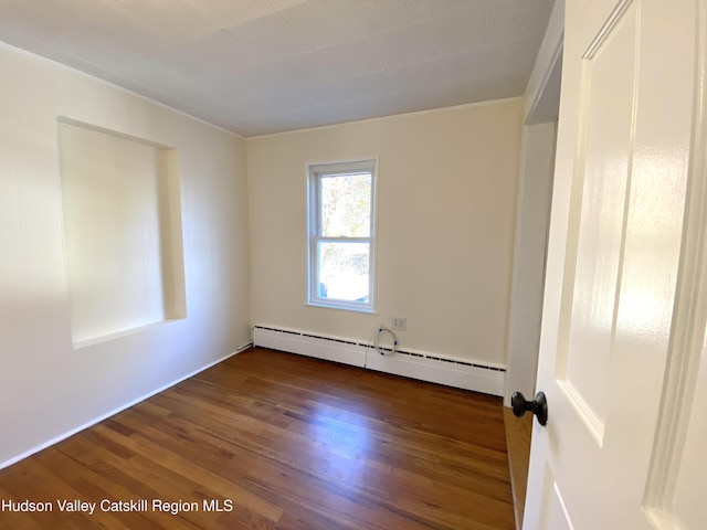 spare room featuring ornamental molding, dark hardwood / wood-style flooring, and a baseboard heating unit