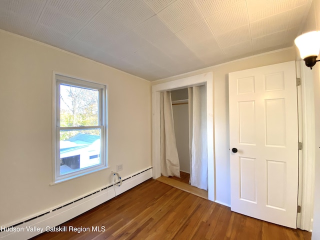 unfurnished bedroom featuring a closet, a baseboard radiator, and dark hardwood / wood-style floors