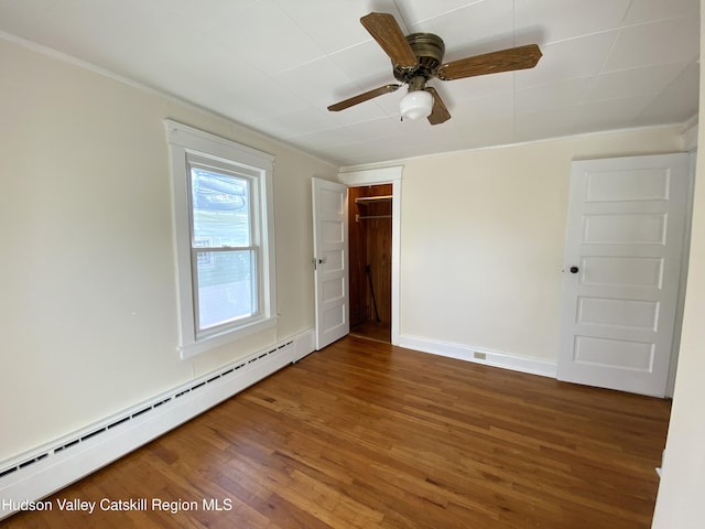 empty room with dark hardwood / wood-style flooring, baseboard heating, and ceiling fan