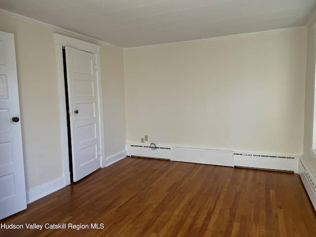 empty room featuring dark hardwood / wood-style floors, baseboard heating, and ornamental molding