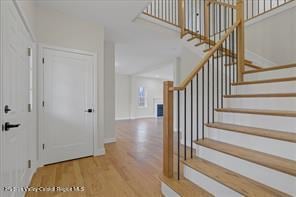 foyer entrance featuring wood finished floors, stairs, and baseboards