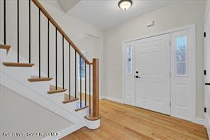 entrance foyer featuring light wood-type flooring, stairs, plenty of natural light, and baseboards