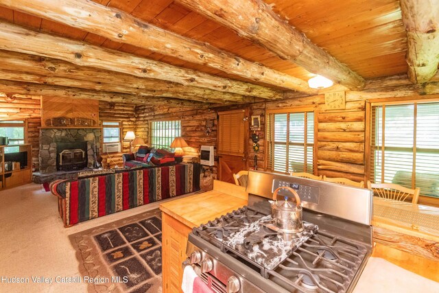 kitchen with a wood stove, stainless steel gas stove, rustic walls, and a healthy amount of sunlight