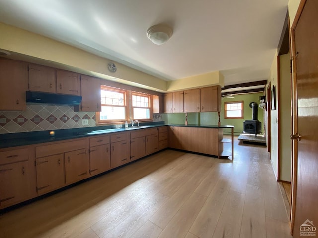 20 Joslen Pl, Hudson, NY 12534 - kitchen with under cabinet range hood, plenty of natural light, light wood-style flooring, and a wood stove