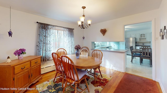 dining area featuring a baseboard radiator, sink, a chandelier, and light hardwood / wood-style floors