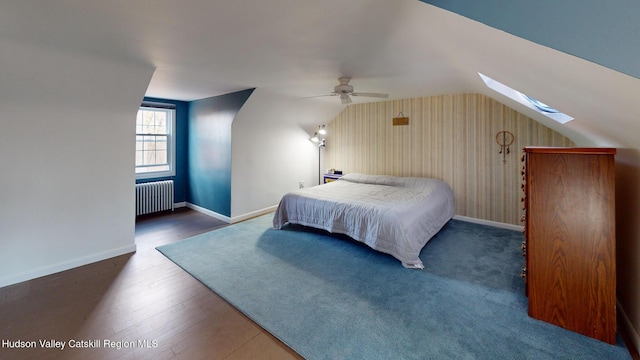 bedroom featuring dark wood-type flooring, ceiling fan, radiator heating unit, and lofted ceiling with skylight