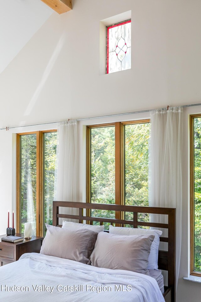 bedroom with multiple windows, beamed ceiling, and high vaulted ceiling