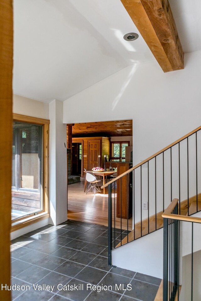 stairway featuring vaulted ceiling with beams and hardwood / wood-style floors