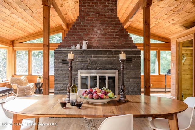 dining room featuring a fireplace, vaulted ceiling with beams, a wealth of natural light, and wooden ceiling