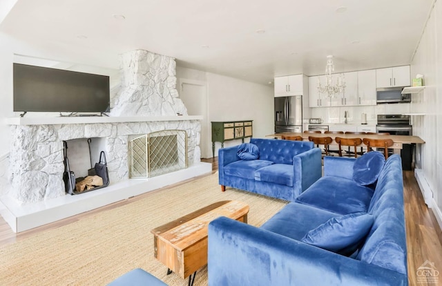 59 Scribner Hollow Rd # B-2, Hunter, NY 12442 - living room with wood finished floors, a stone fireplace, and a chandelier