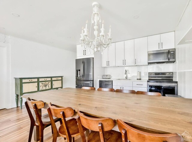 59 Scribner Hollow Rd # B-2, Hunter, NY 12442 - kitchen with appliances with stainless steel finishes, a sink, a chandelier, white cabinetry, and light wood-style flooring