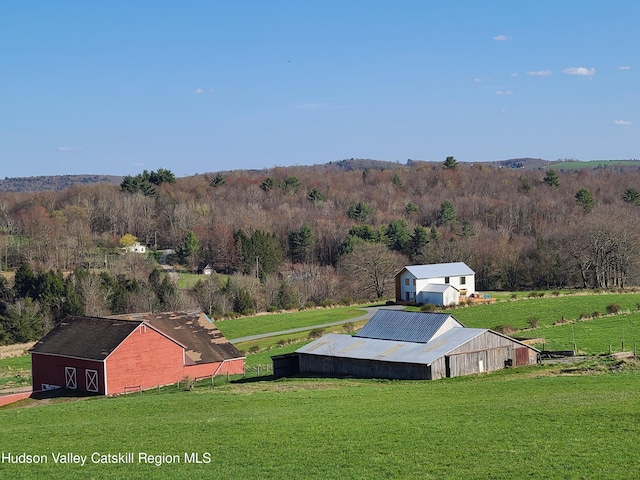 entry to storm shelter with a lawn, a rural view, and an outdoor structure