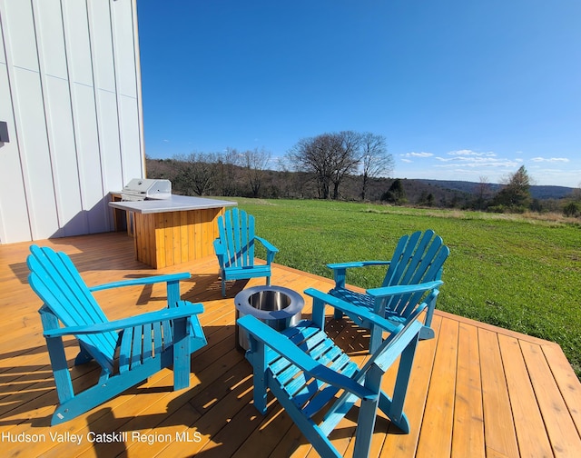 wooden terrace with a lawn and area for grilling