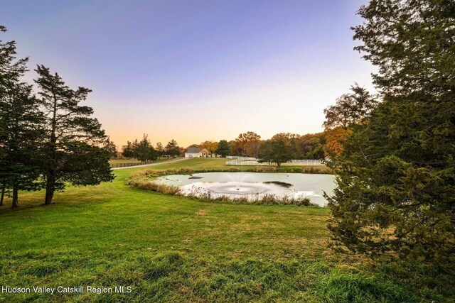 yard at dusk featuring a water view