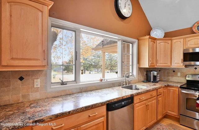 kitchen with backsplash, dark stone counters, sink, light wood-type flooring, and appliances with stainless steel finishes