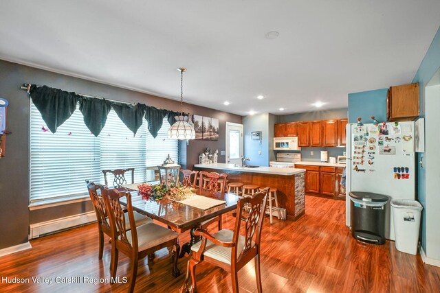 dining room with hardwood / wood-style flooring, baseboard heating, and sink