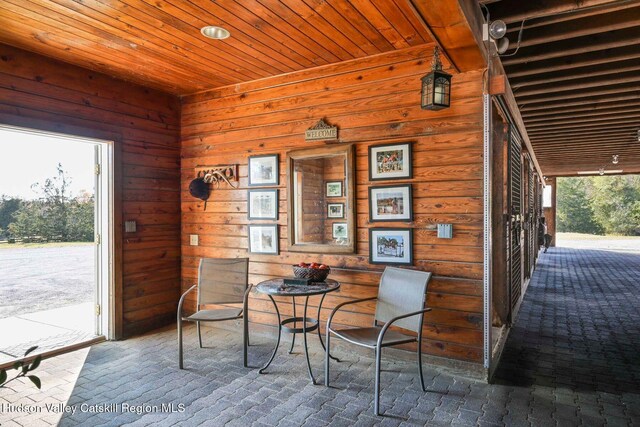 dining area featuring wooden ceiling and wooden walls