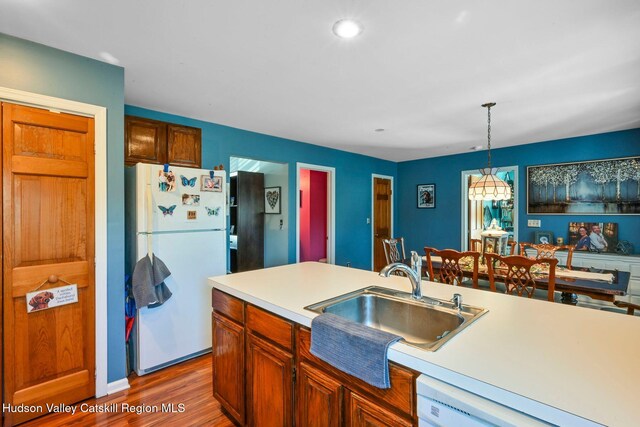 kitchen with dark wood-type flooring, sink, decorative light fixtures, and white appliances