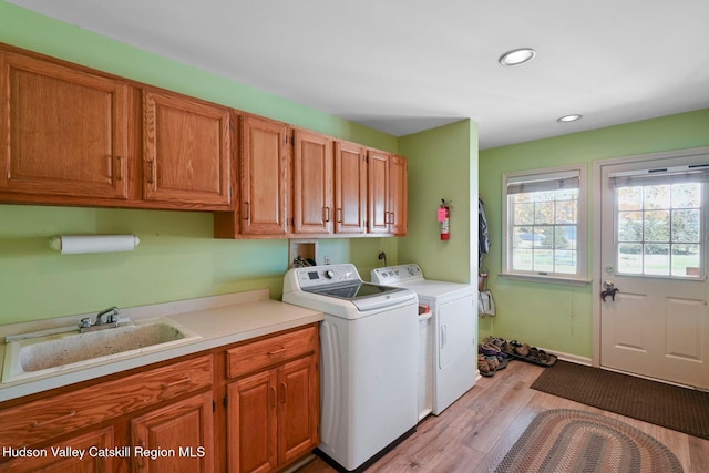 laundry room featuring cabinets, light wood-type flooring, sink, and washing machine and clothes dryer