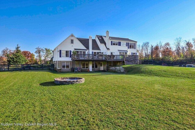 rear view of house featuring a yard, a deck, and a fire pit