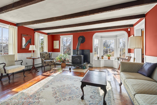 55 Church Ave, Germantown, NY 12526 - living area with a wood stove, beamed ceiling, a wainscoted wall, and hardwood / wood-style floors