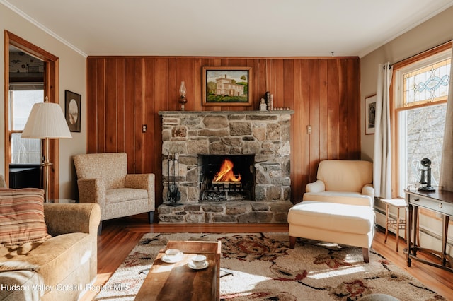 living room featuring hardwood / wood-style floors, wooden walls, ornamental molding, and a fireplace