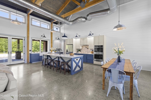 1248 Albany Post Rd, Gardiner, NY 12525 - kitchen featuring appliances with stainless steel finishes, a towering ceiling, light countertops, blue cabinetry, and a kitchen breakfast bar
