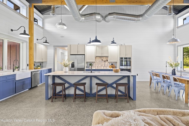 1248 Albany Post Rd, Gardiner, NY 12525 - kitchen with stainless steel appliances, blue cabinetry, dark aggregate flooring, light countertops, and a towering ceiling