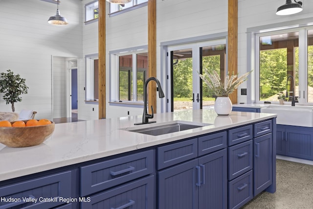 1248 Albany Post Rd, Gardiner, NY 12525 - kitchen featuring a sink, blue cabinetry, wooden walls, hanging light fixtures, and a high ceiling
