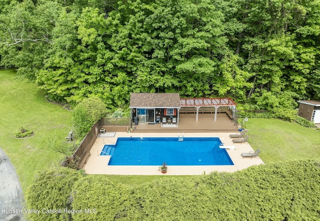outdoor pool with a diving board, a yard, fence, an outdoor structure, and a wooden deck