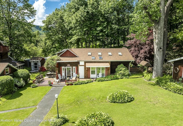 view of front of house featuring roof with shingles, an outbuilding, a front yard, and fence