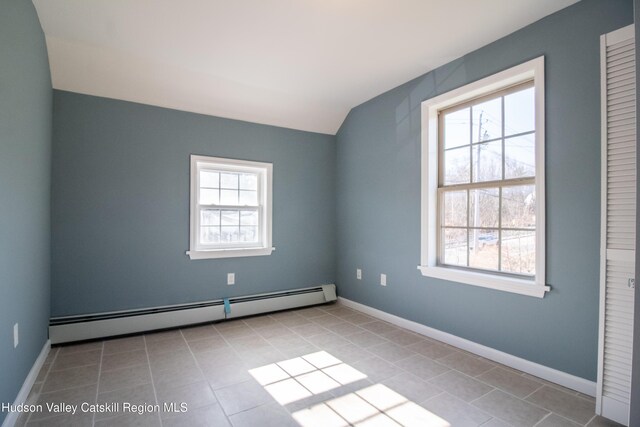 tiled empty room featuring baseboard heating and lofted ceiling