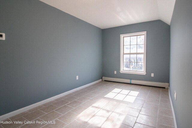 spare room featuring baseboard heating, lofted ceiling, and light tile patterned flooring