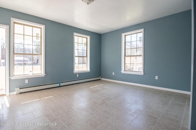 empty room with plenty of natural light, light tile patterned floors, and baseboard heating