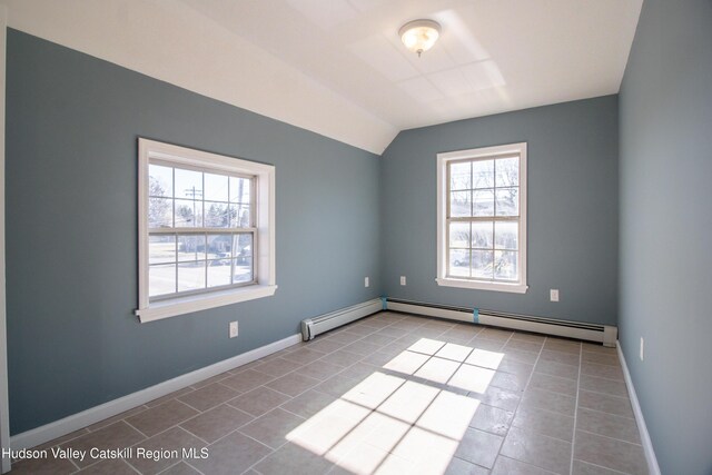 tiled spare room featuring lofted ceiling, a baseboard radiator, and a healthy amount of sunlight