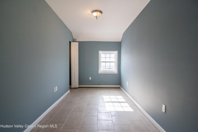 tiled empty room featuring vaulted ceiling and a baseboard radiator