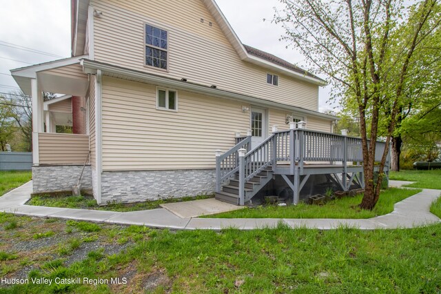 rear view of house with a lawn and a wooden deck