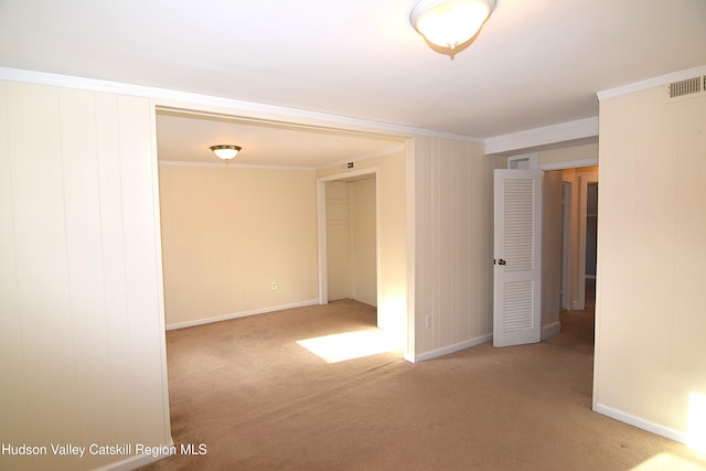 spare room with ornamental molding and light carpet