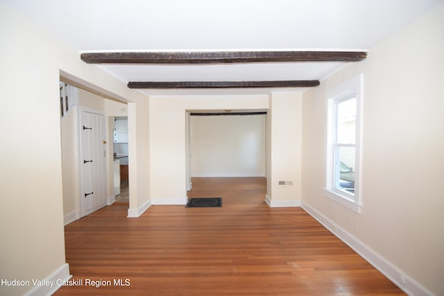 unfurnished room featuring beam ceiling and hardwood / wood-style floors