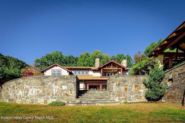 exterior space with a yard, stone siding, and a chimney