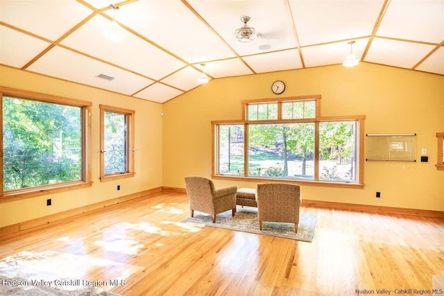 unfurnished room featuring baseboards, wood finished floors, lofted ceiling, and visible vents