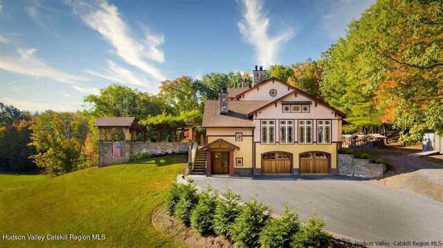 view of front of home with aphalt driveway, an attached garage, stairway, a front lawn, and a chimney
