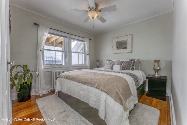 bedroom featuring a ceiling fan, crown molding, radiator heating unit, and wood finished floors