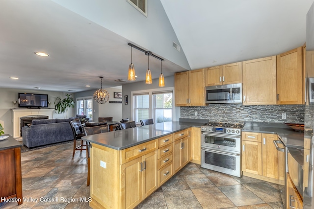 kitchen featuring visible vents, decorative backsplash, dark countertops, a peninsula, and stainless steel appliances