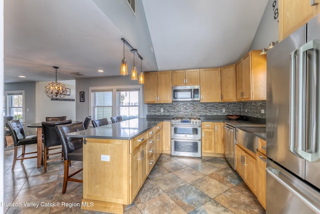 kitchen featuring a breakfast bar, dark countertops, backsplash, appliances with stainless steel finishes, and a peninsula