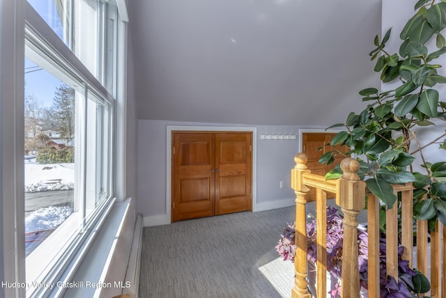 carpeted entryway featuring lofted ceiling and baseboards