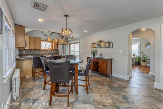 dining area with plenty of natural light, radiator heating unit, visible vents, and arched walkways