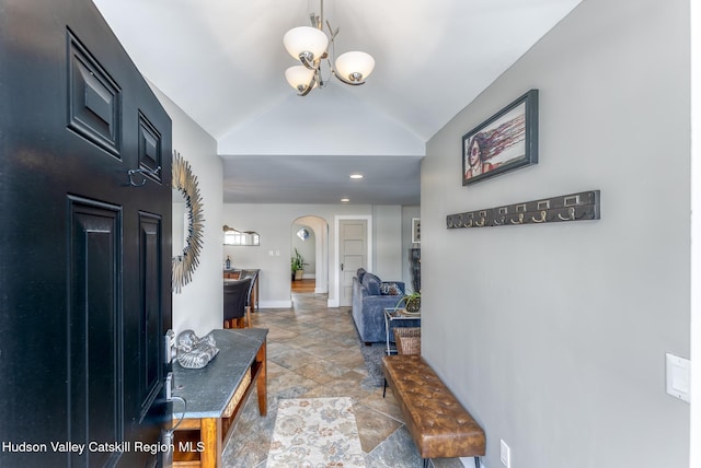 entrance foyer with lofted ceiling, baseboards, stone finish floor, and arched walkways